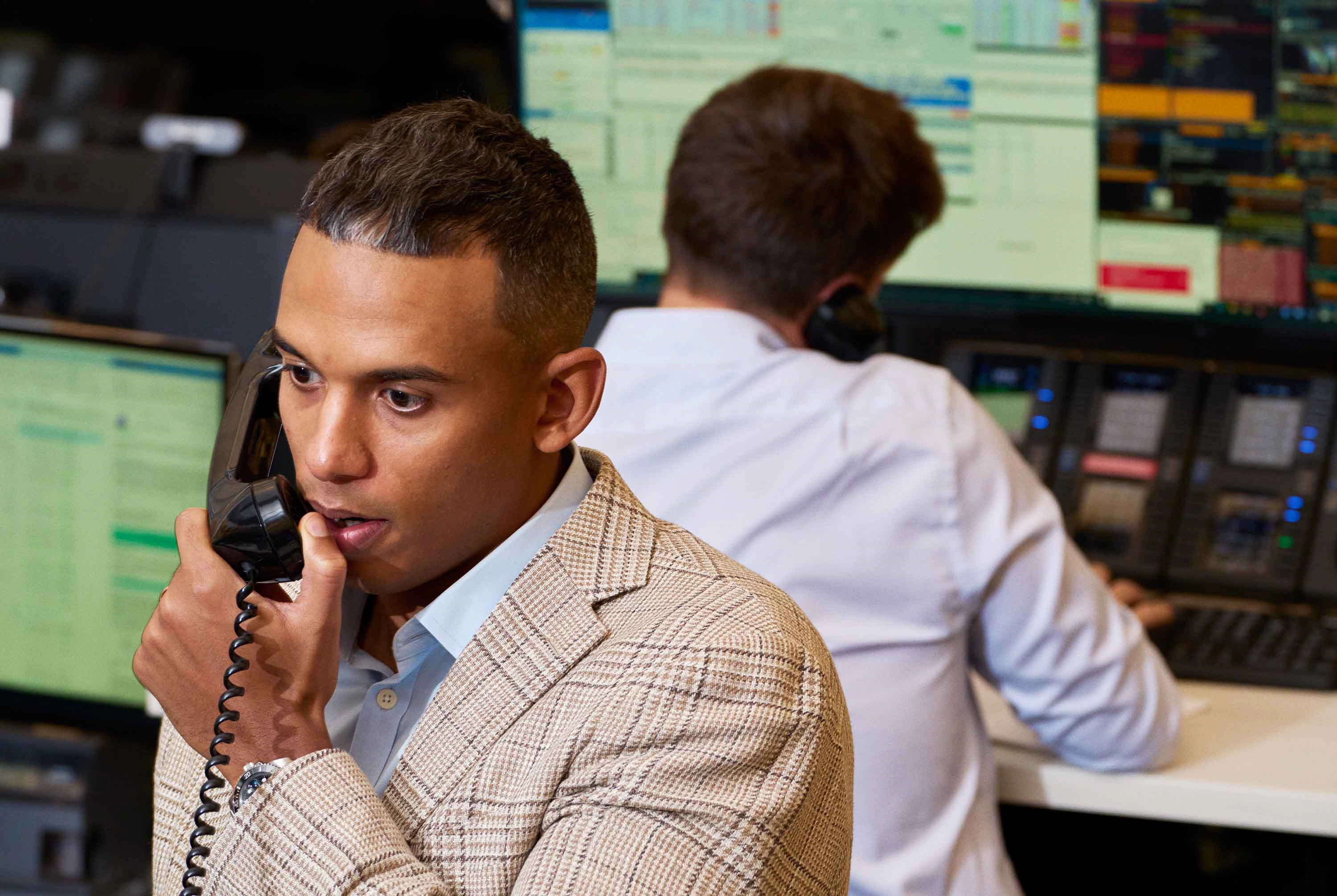 A person managing their finances on a laptop and phone, with a  Bright Stone card nearby